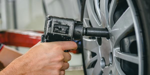 Person using an impact wrench to tighten a car wheel.