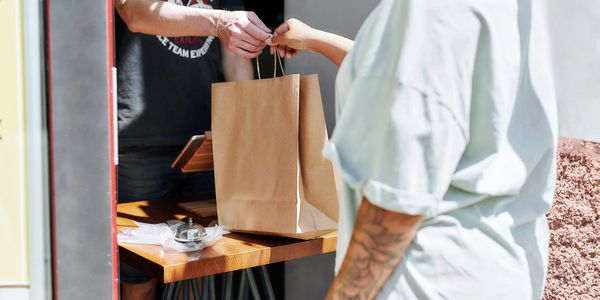 Person receiving a paper bag at a counter.