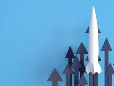 White rocket surrounded by upward black arrows on blue background.