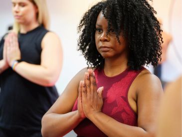 Two women practicing yoga with hands in prayer position.