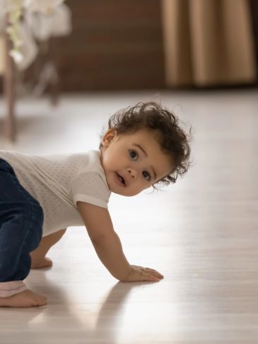 Curious baby crawling on a wooden floor.
