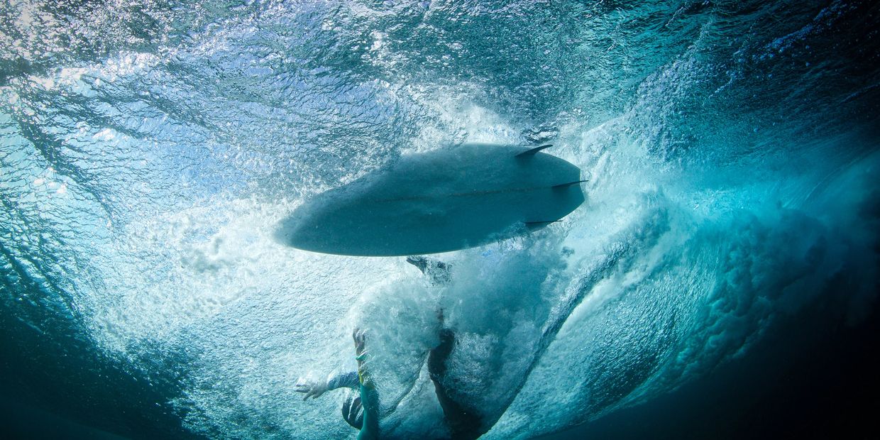 Woman watching a water polo game in a pool, seen from behind.
