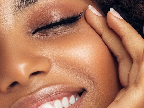 Close-up of a smiling woman with flawless skin and natural makeup.