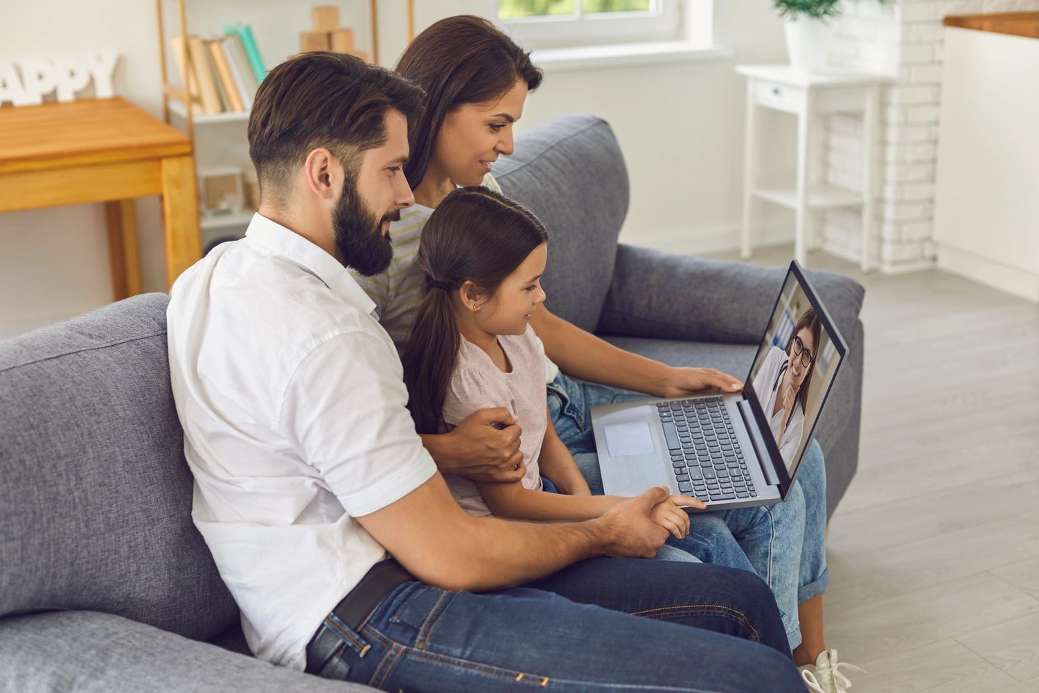 Family therapy video appointment with a female therapist on a laptop at home.