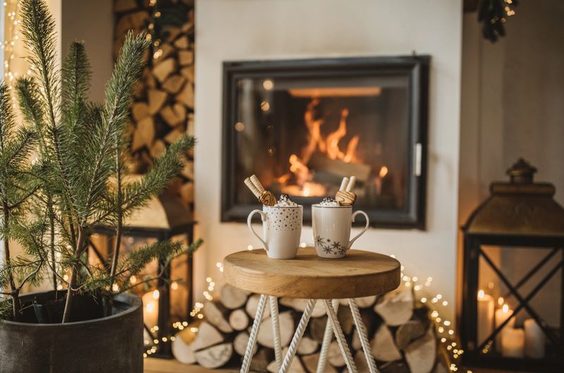 Cozy living room winter interior with fireplace, two cups with hot chocolate waiting to be drunk.