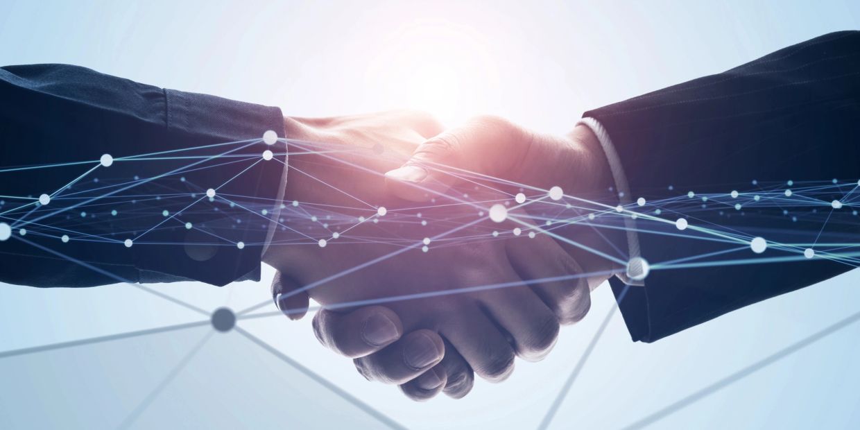 Two people shaking hands with digital network overlay.