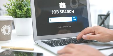 Person searching for a job on a laptop at a clean desk.