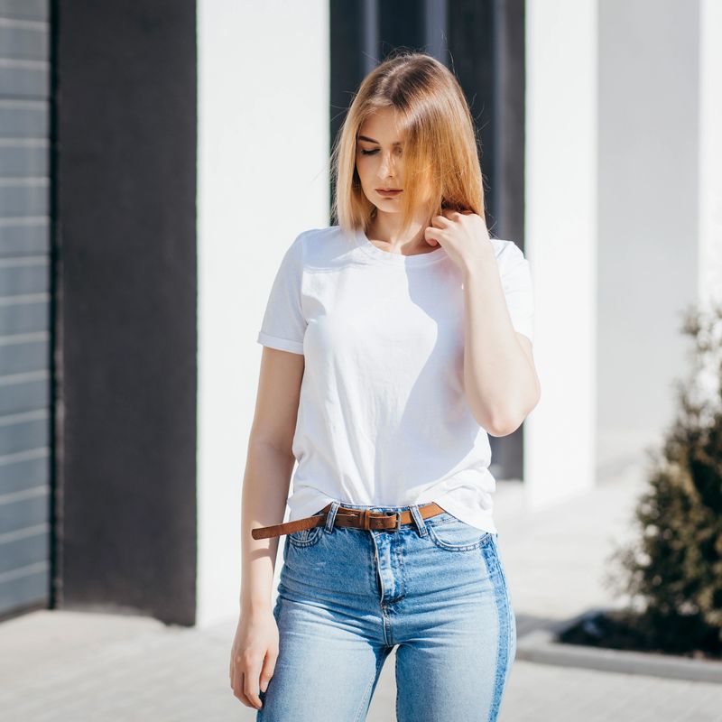 Girl in sunglasses wearing white t-shirt posing against street , urban clothing style. Street photography