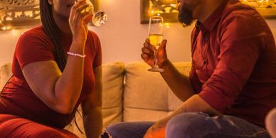 Couple enjoying drinks together in a cozy room with warm lighting.