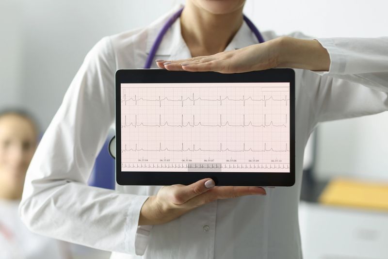 Doctor holding tablet with electrocardiogram in clinic closeup. Diagnosis of heart rhythm disorders concept