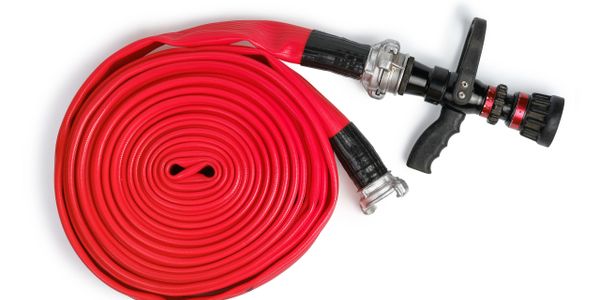 Coiled red fire hose with nozzle on white background.