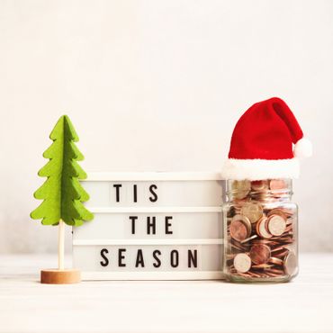 Christmas-themed display with a jar of coins wearing a Santa hat and a green felt tree.