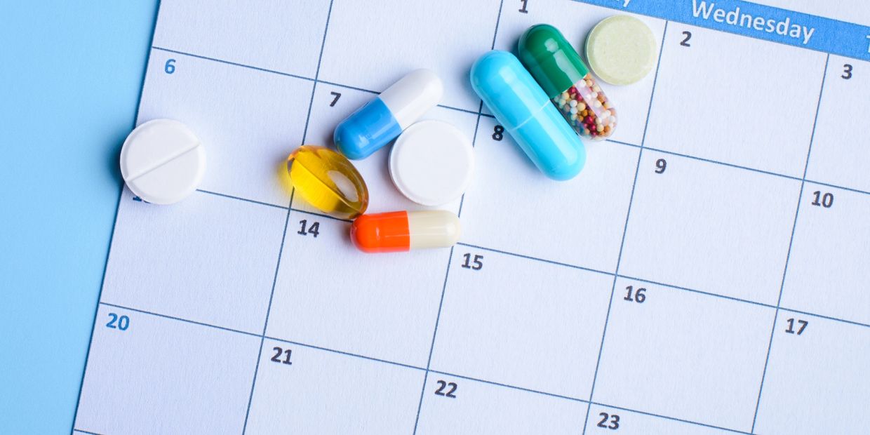 Various pills on a calendar background.