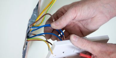 Hands connecting electrical wires to a switch.