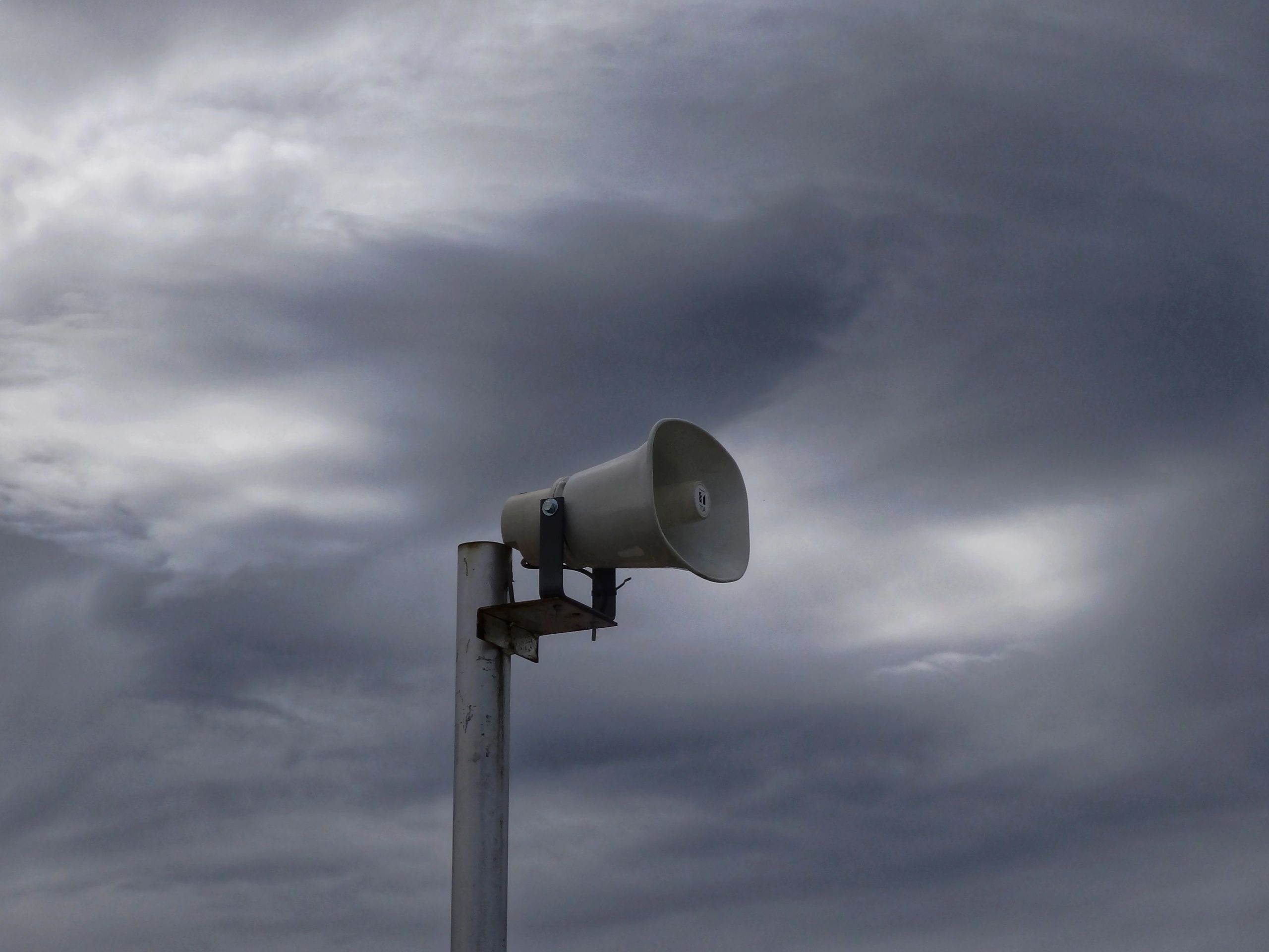 Outdoor loudspeaker against cloudy sky.