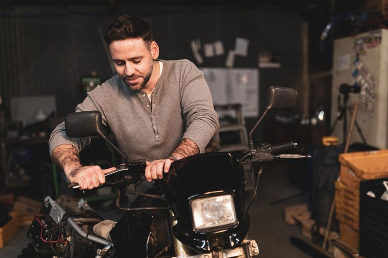 Young man repairing motorcycle in repair shop