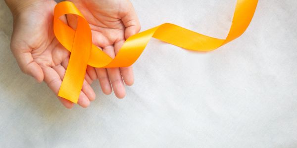 Hands holding an orange awareness ribbon.