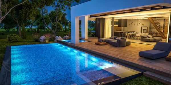 Modern house with illuminated swimming pool at night and open living area.