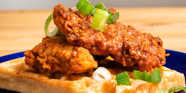 Crispy fried chicken served on a golden waffle, garnished with green onions.
