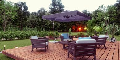 Outdoor wooden deck with cozy seating and umbrella surrounded by greenery.