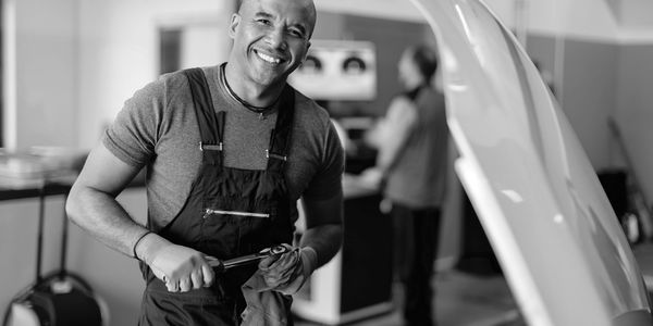 Smiling mechanic fixing a car engine.