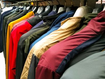 A rack of colorful jackets hanging on hangers in a store.