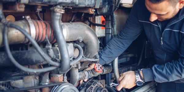 Mechanic repairing a complex engine system with a wrench.