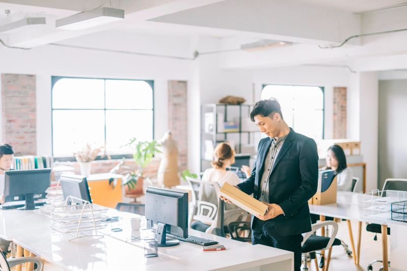 Man receiving a package at workplace. Coworkers working on the background.