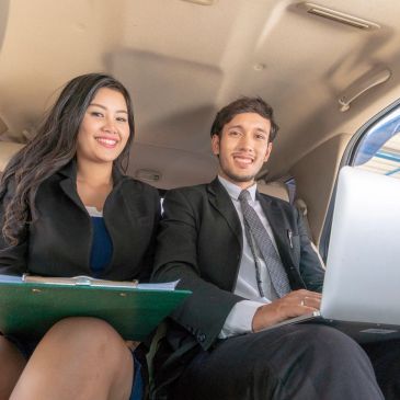 Dos jóvenes profesionales sonrientes en un auto.