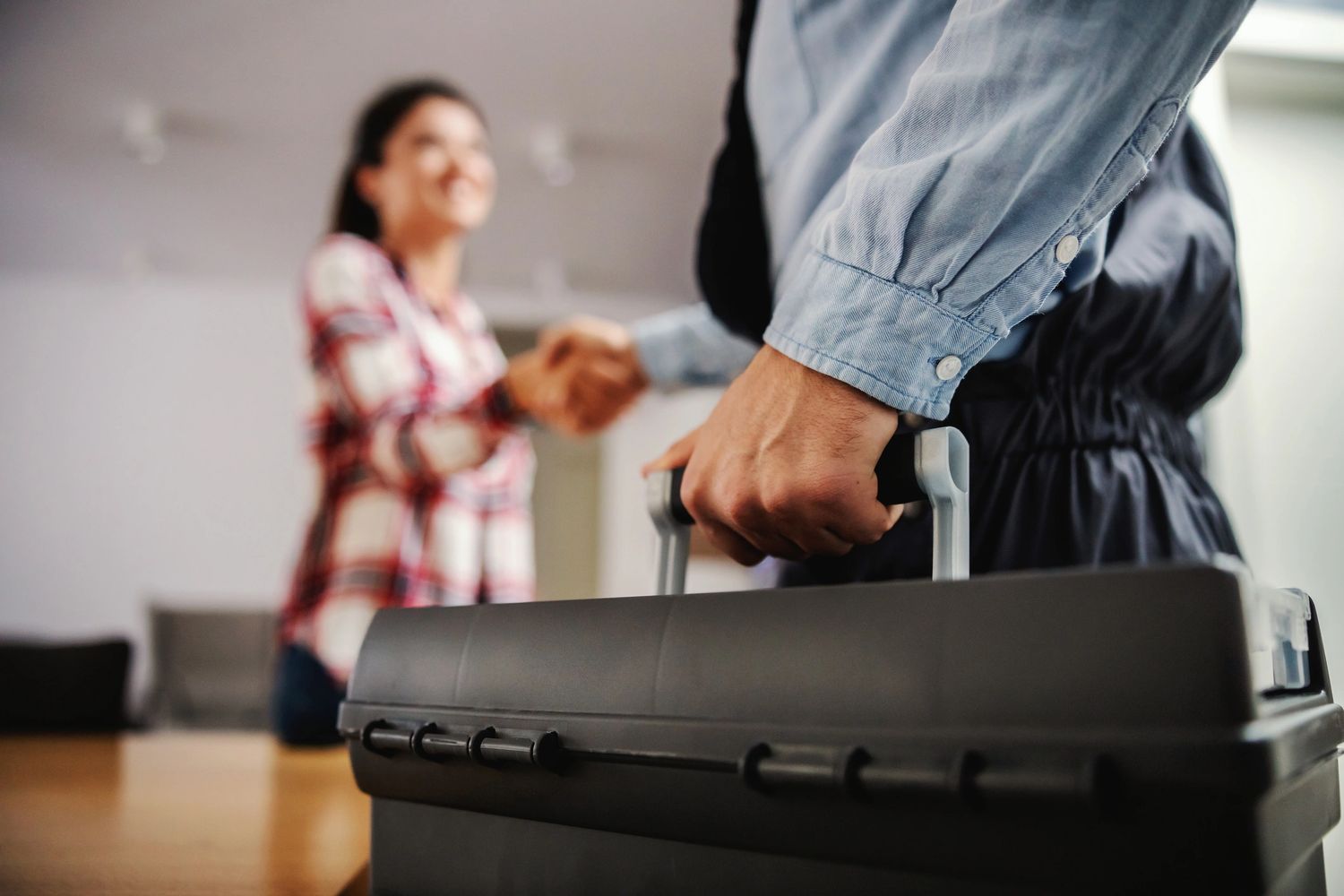 Two people shaking hands, one holding a toolbox.
