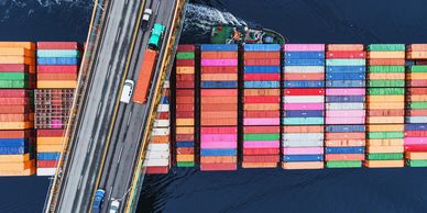 Aerial view of a cargo ship passing under a bridge.