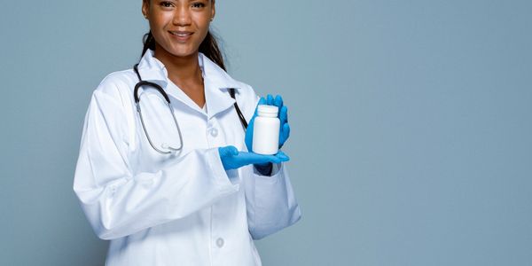 Smiling female doctor in lab coat holding a white medicine bottle.