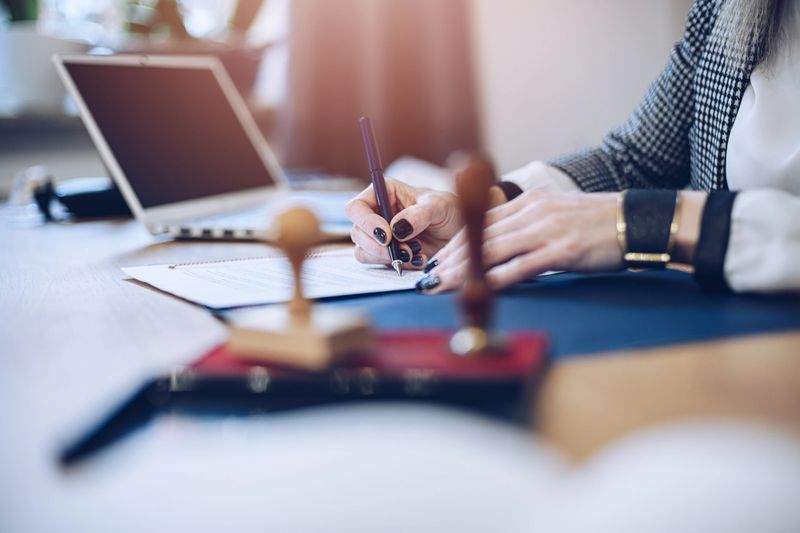 Woman notary public signing and notarizing contract document in her law office