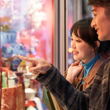 A happy couple window shopping and pointing at items.