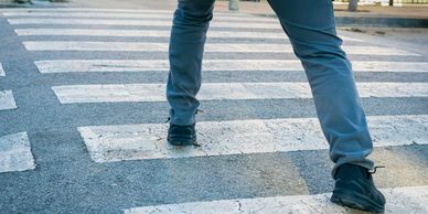 Person walking across a worn pedestrian crosswalk.