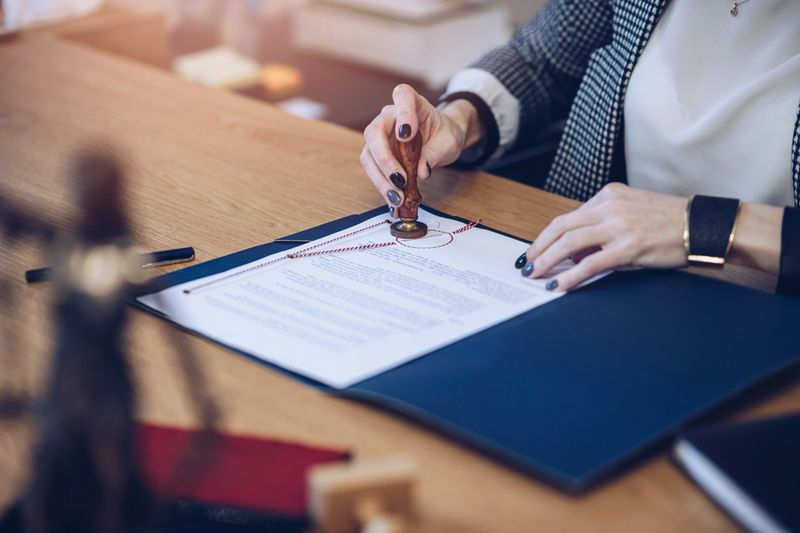 A woman notary, a lawyer stamps the seal on the documents.