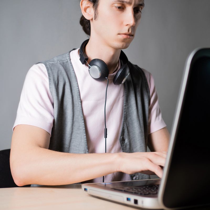 Write code and learn programming languages. A student or specialist is doing a project. The guy is a programmer working on a laptop