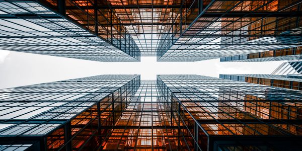 Looking up at modern glass skyscrapers with orange reflections.
