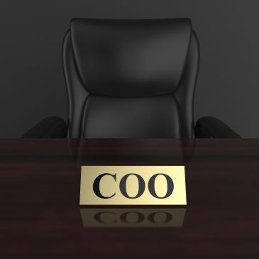 Empty COO office chair behind a desk nameplate.