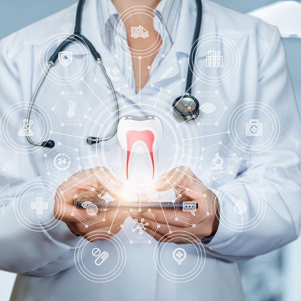 Doctor holding a phone with a glowing tooth and medical icons.