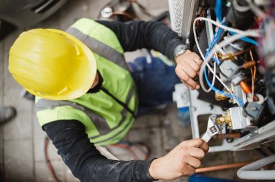 Worker fixing machinery with wrench.