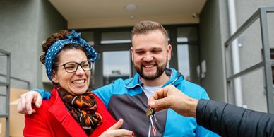 Happy couple receiving keys to their new home outside the entrance.