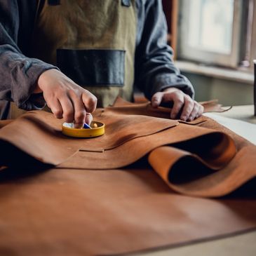 Craftsman marking leather for cutting in a workshop.