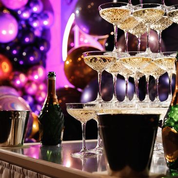 Champagne cascading down a pyramid of glasses at a festive party.