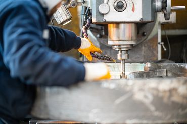 Worker operating a milling machine wearing gloves.