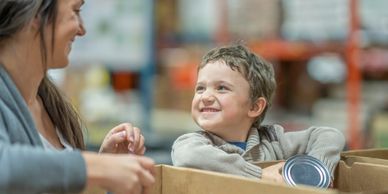 Parent and child preparing items while volunteering for Cola Kids Consignment