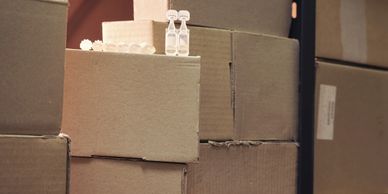 Cardboard boxes stacked with small glass ampoules on top.