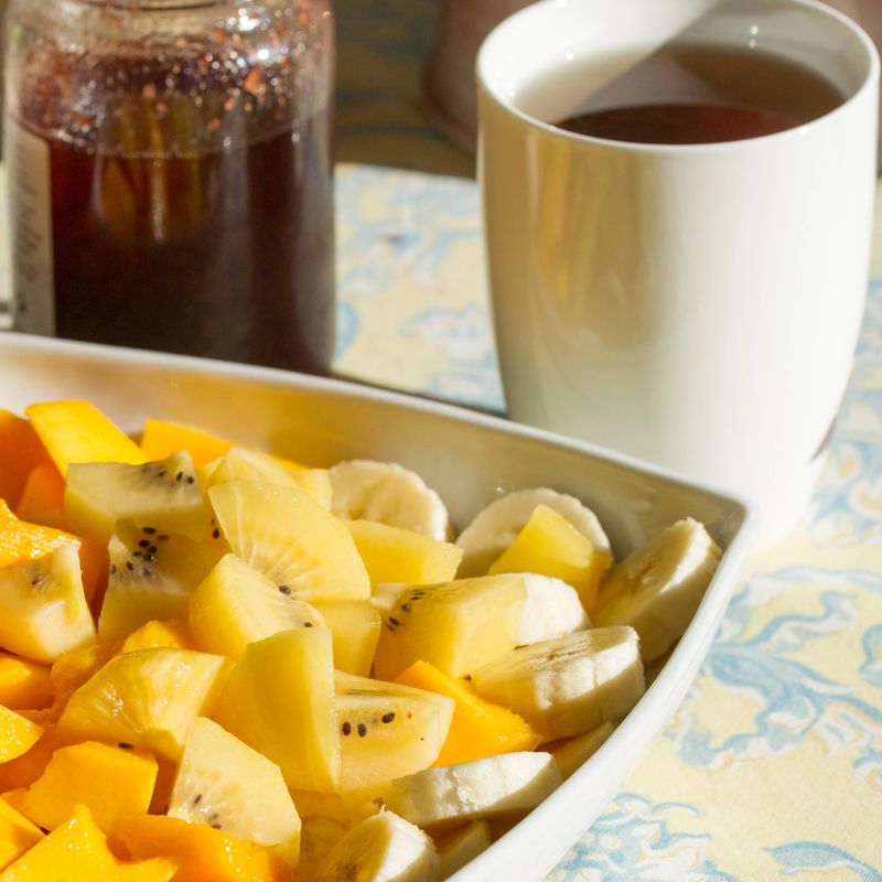 Large plate of fresh exotic fruits for breakfast, mango, bananas, golden kiwi on a table