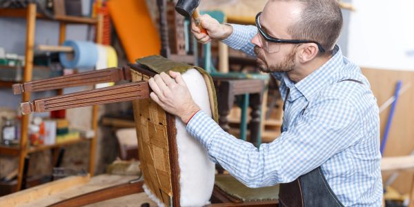 Man repairing a wooden chair in a workshop.