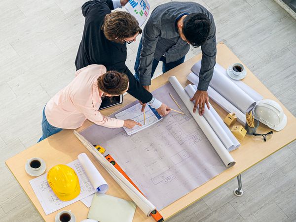 Team of architects collaborating over blueprints and charts at a desk.